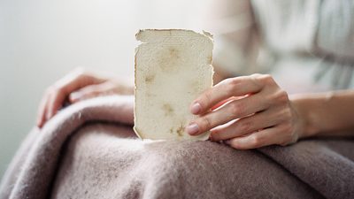 Одна карта таро в пальцах женщины, мягкий рассеянный свет пасмурного утра